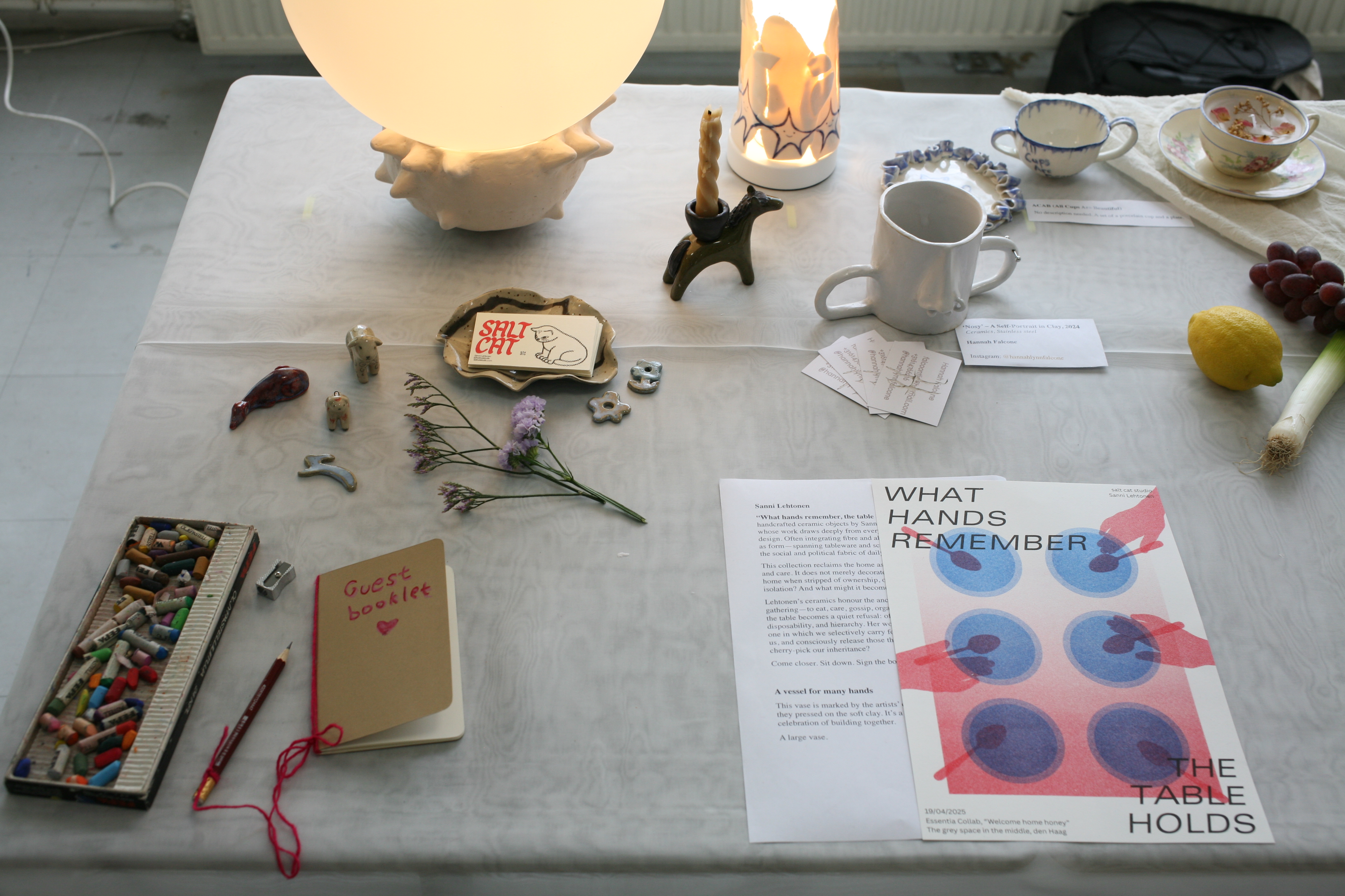 Long table installation view with ceramic vessels and textiles